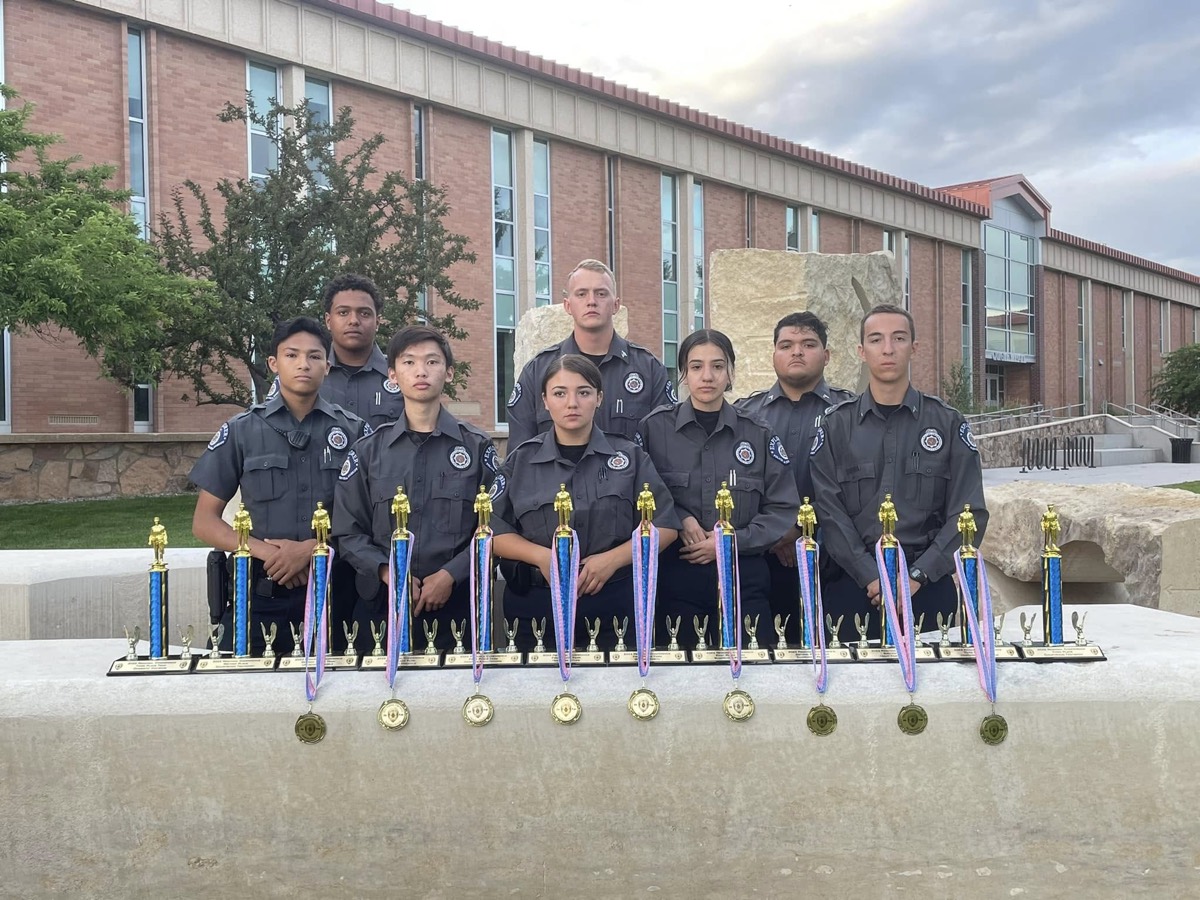 Explorers lined up behind a table of trophies and medals outside the state conference
