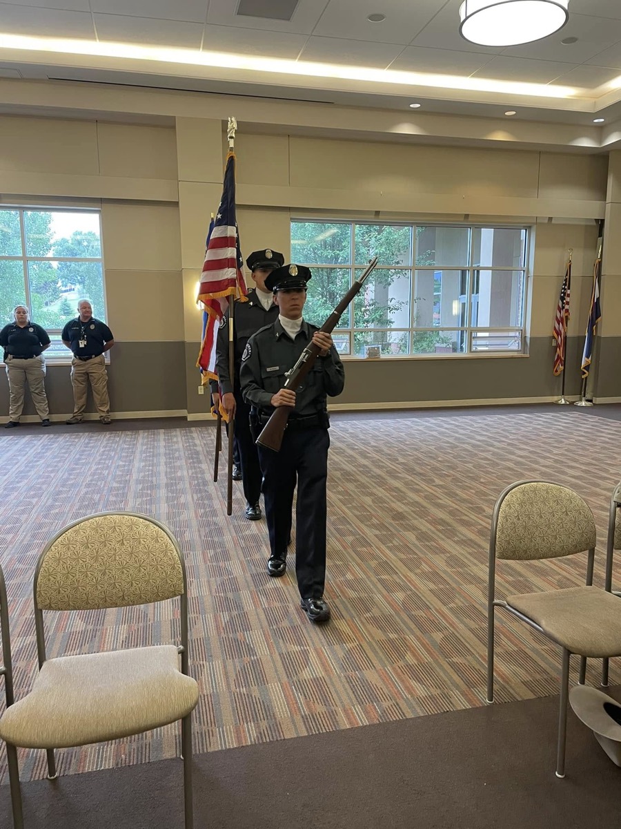 Explorer color guard marching with rifles and flags at a ceremony